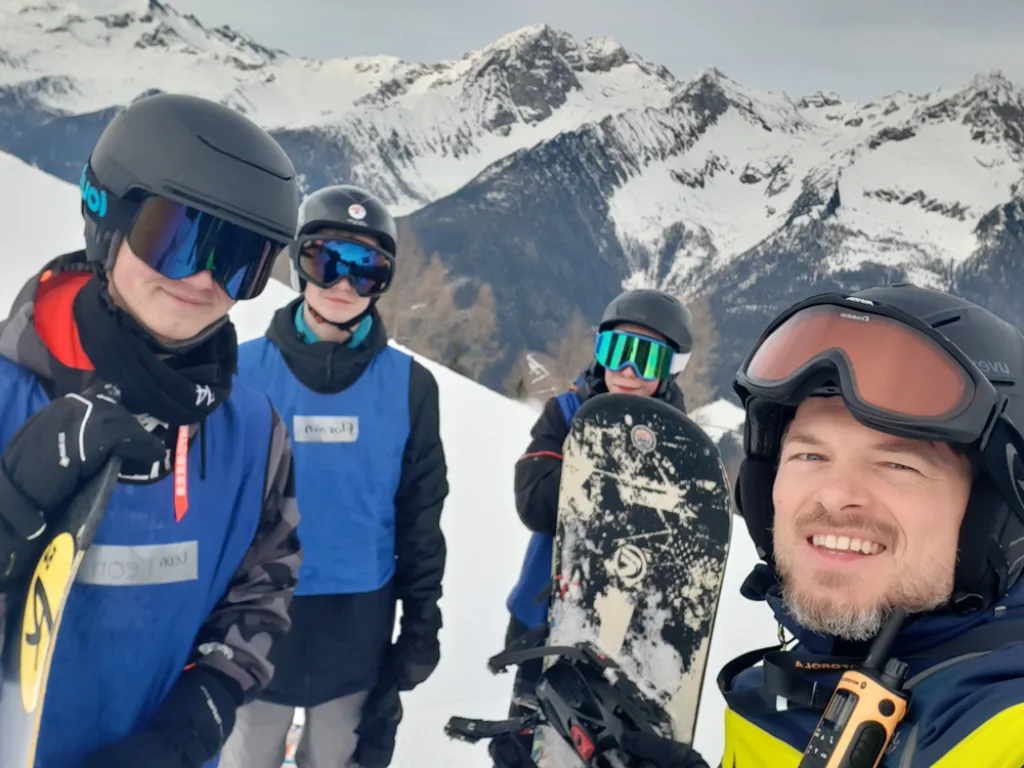 Selfie mehrerer Jugendlicher mit Helm und Skibrille auf der Piste.